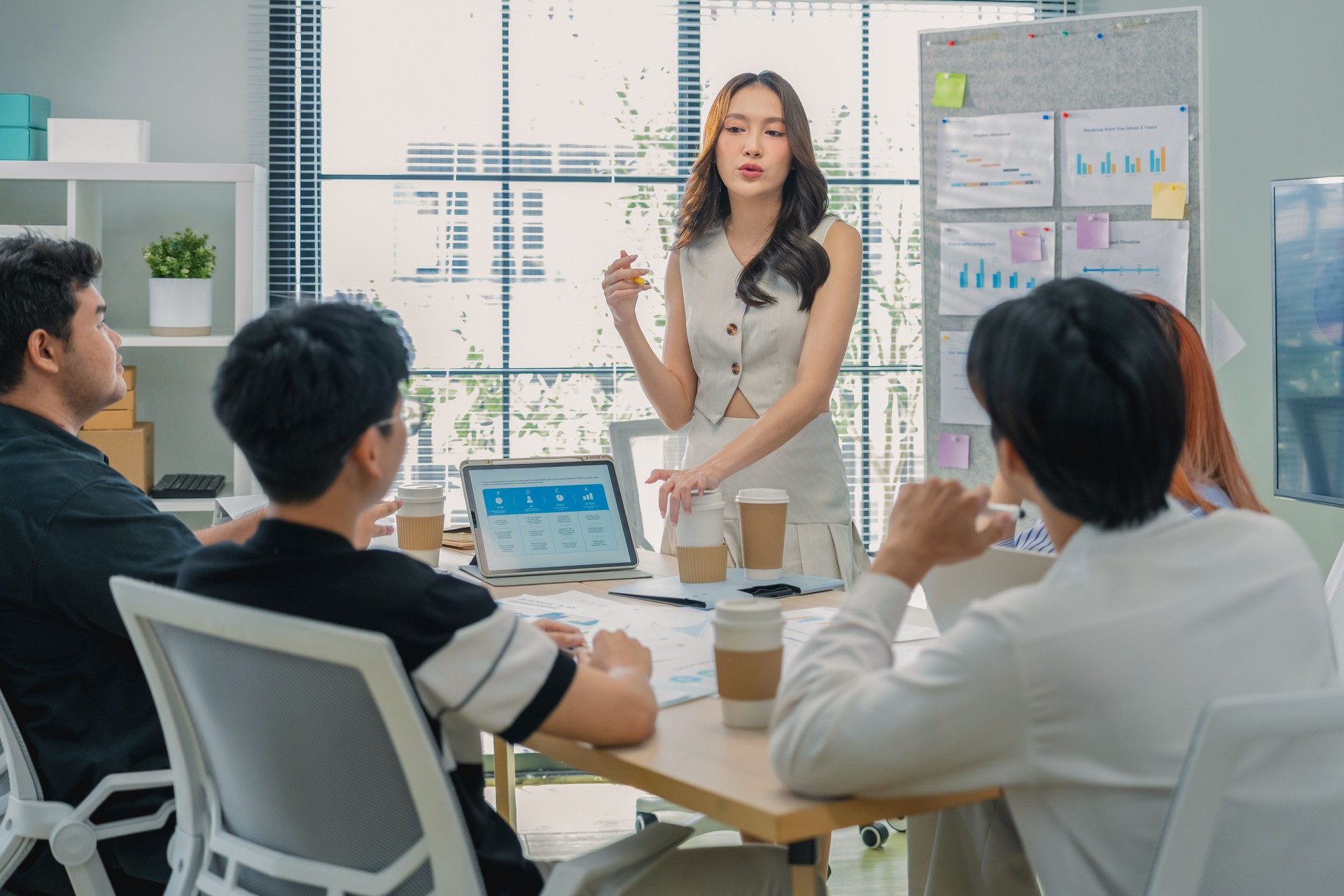 Female executive leads strategic brainstorming session using flipchart methodology, facilitating cross-functional ideation with business partners through data-driven innovation and agile frameworks