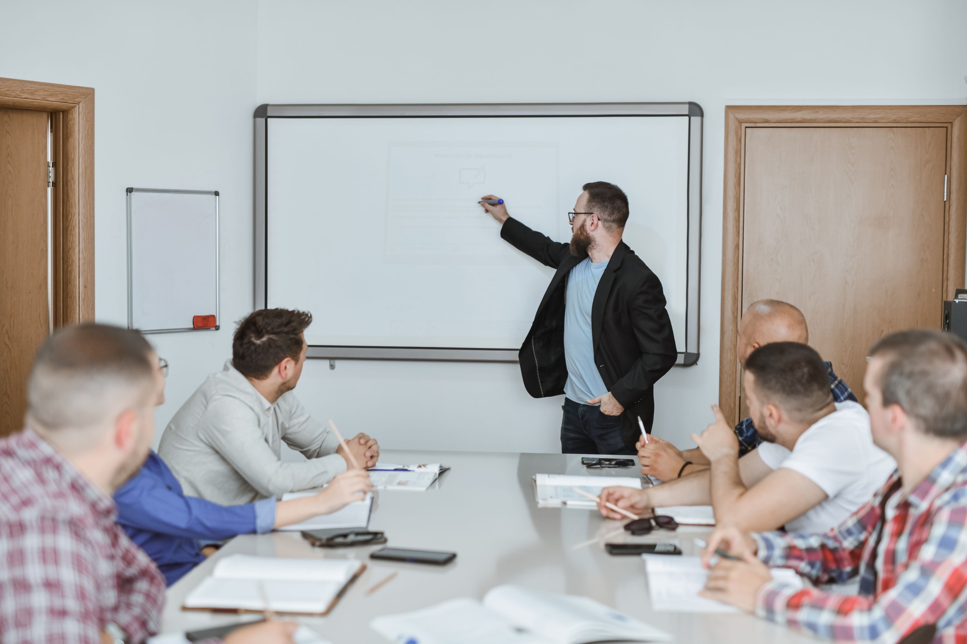 Male Adult Presenting on White Board on Educational Seminar in Classroom